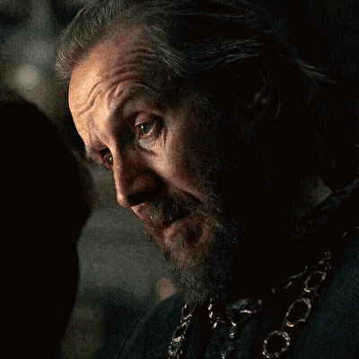 A Man With A Beard And A Chain Around His Neck Looks At The Camera GIF
