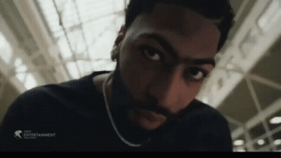 A Man With A Beard And A Chain Around His Neck Looks At The Camera GIF