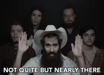 A Man With A Beard And A Cowboy Hat Says Not Quite But Nearly There In Front Of A Group Of Men GIF