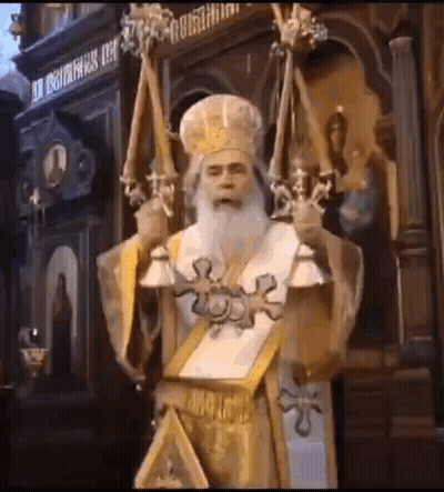 A Man With A Beard And A Crown Is Holding Candles And A Book In A Church . GIF