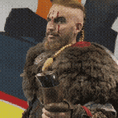 A Man With A Beard And A Fur Coat Is Holding A Sword . GIF