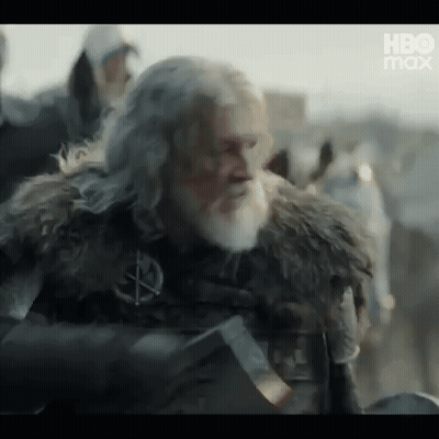 A Man With A Beard And A Fur Coat Is Holding A Sword In His Hand . GIF