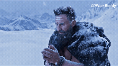 A Man With A Beard And A Fur Coat Is Standing In The Snow With Mountains In The Background GIF