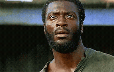 A Man With A Beard And A Green Shirt Is Looking At The Camera With A Surprised Look On His Face . GIF