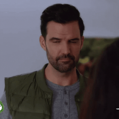 A Man With A Beard And A Green Vest Is Making A Funny Face . GIF