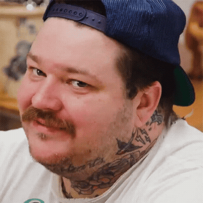 A Man With A Beard And A Hat Has A Tattoo On His Neck GIF