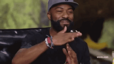 A Man With A Beard And A Hat Is Clapping His Hands . GIF