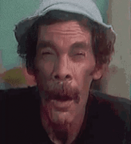 A Man With A Beard And A Hat Is Making A Funny Face With His Eyes Closed . GIF