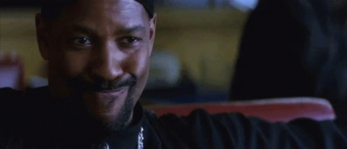 A Man With A Beard And A Hat Is Sitting In A Chair And Talking To Someone . GIF