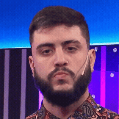 A Man With A Beard And A Nose Ring Is Wearing A Paisley Shirt And Making A Funny Face . GIF