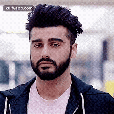 A Man With A Beard And A Pink Shirt Is Wearing A Black Jacket And A Pink Shirt . GIF