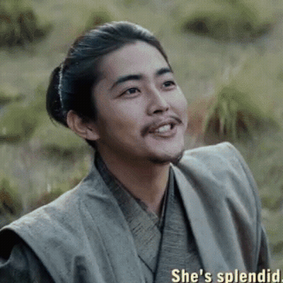 A Man With A Beard And A Ponytail Is Smiling While Wearing A Kimono . GIF