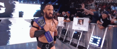 A Man With A Beard And A Purple Belt Stands In Front Of A Crowd Of People . GIF