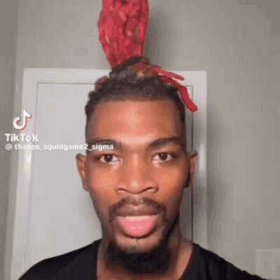 A Man With A Beard And A Red Headband On His Head Is Smiling And Looking At The Camera . GIF