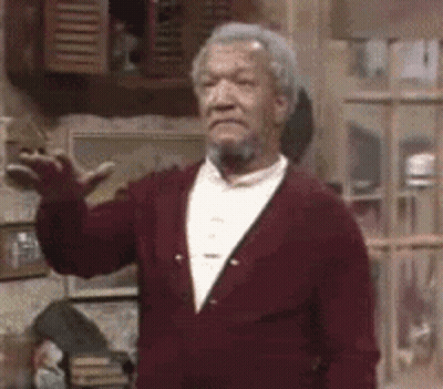 A Man With A Beard And A Red Jacket Is Standing In A Room . GIF