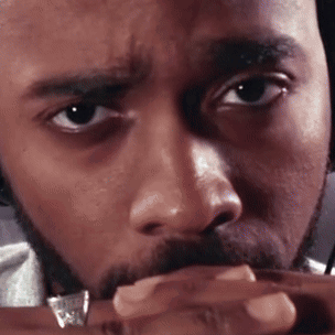A Man With A Beard And A Ring On His Finger Looks At The Camera GIF