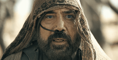 A Man With A Beard And A Scarf Around His Head Looks At The Camera GIF