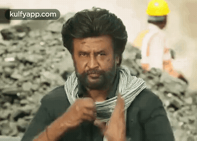 A Man With A Beard And A Scarf Around His Neck Is Holding A Roll Of Wire . GIF
