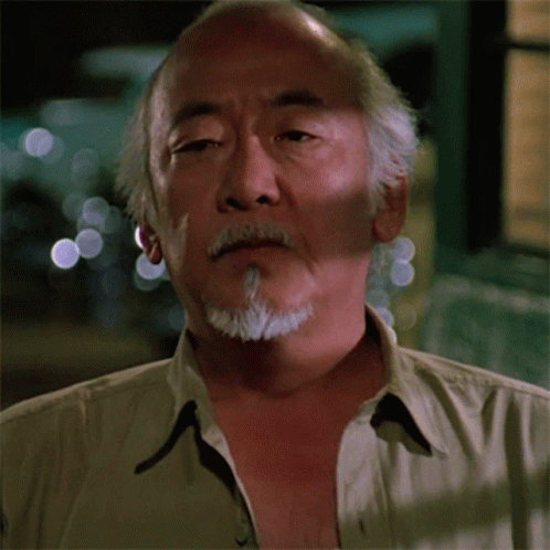 A Man With A Beard And A Tan Shirt Is Looking At The Camera GIF