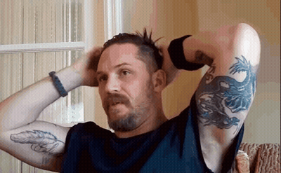 A Man With A Beard And A Tattoo On His Arm Is Holding His Hair In His Hands . GIF