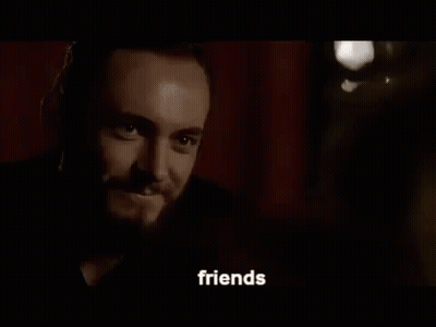 A Man With A Beard And A Tattoo On His Face Is Talking To Someone In A Dark Room . GIF