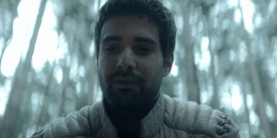 a man with a beard and a white jacket looks at the camera