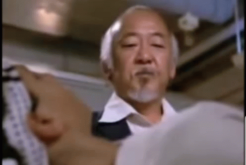 A Man With A Beard And A White Shirt Is Holding A Piece Of Paper . GIF