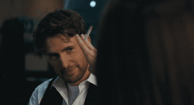 A Man With A Beard And A White Shirt Is Looking At A Woman GIF