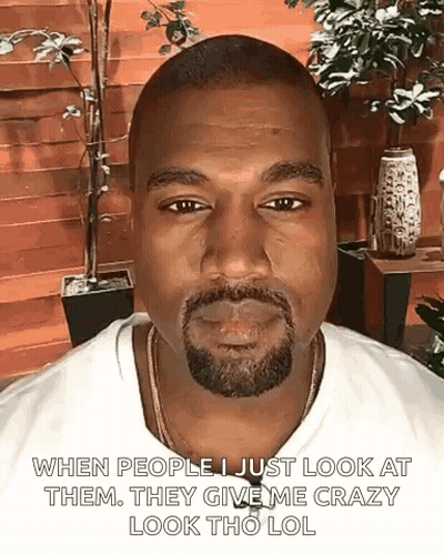 A Man With A Beard And A White Shirt Is Smoking A Cigarette And Making A Funny Face . GIF