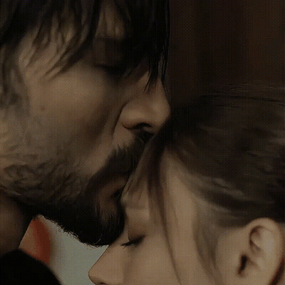 A Man With A Beard And A Woman With Long Hair Are Touching Their Noses GIF