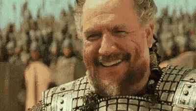 A Man With A Beard And Armor Is Smiling In Front Of A Crowd Of Soldiers . GIF