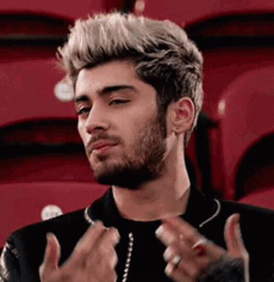 A Man With A Beard And Blonde Hair Is Sitting In A Stadium With Red Seats . GIF