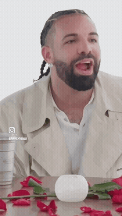 a man with a beard and braids is sitting at a table with roses and a white ball .