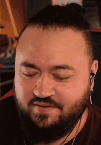 A Man With A Beard And Bun Is Wearing Headphones And Making A Face . GIF