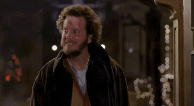 A Man With A Beard And Curly Hair Is Standing In Front Of A Doorway . GIF