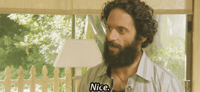 A Man With A Beard And Curly Hair Is Standing In Front Of A Window And Saying Nice . GIF