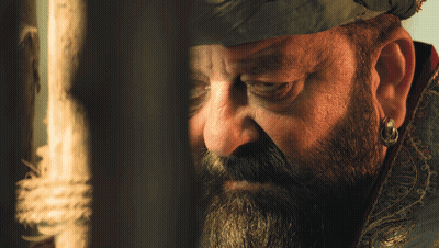 A Man With A Beard And Earring Is Looking Through A Window GIF
