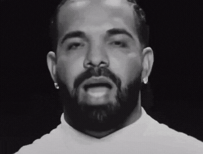 A Man With A Beard And Earrings Looks At The Camera GIF
