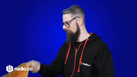 A Man With A Beard And Glasses Is Holding A Megaphone In Front Of A Radio.co Logo GIF