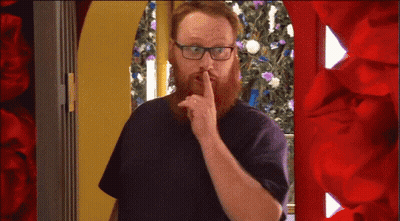 A Man With A Beard And Glasses Is Holding His Finger To His Lips GIF