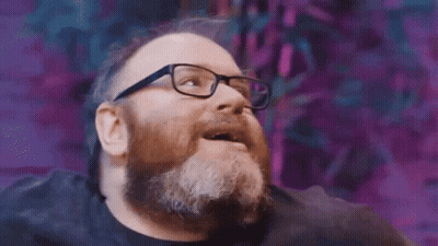 A Man With A Beard And Glasses Is Looking Up And Smiling . GIF