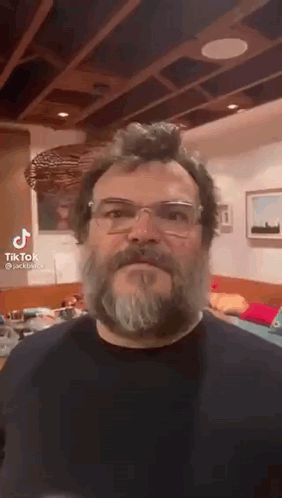 A Man With A Beard And Glasses Is Making A Funny Face . GIF