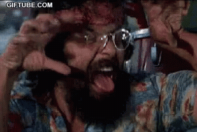A Man With A Beard And Glasses Is Screaming With His Tongue Hanging Out . GIF