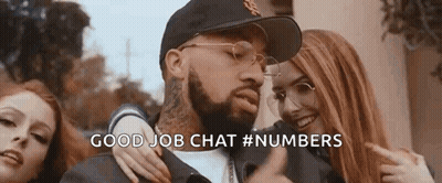 A Man With A Beard And Glasses Is Standing Next To Two Women And Pointing At Them . GIF
