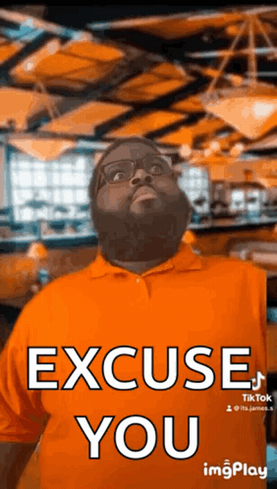 A Man With A Beard And Glasses Is Wearing An Orange Shirt And Making A Funny Face . GIF