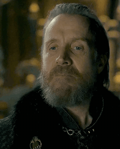 A Man With A Beard And Gray Hair Is Wearing A Black Coat GIF