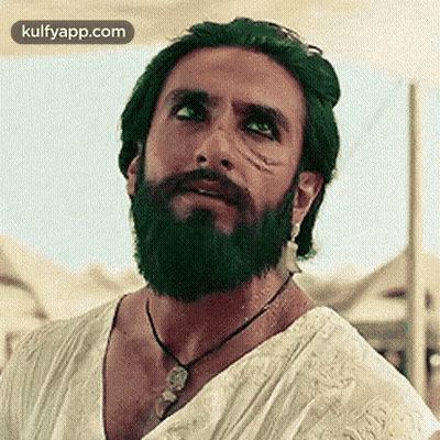 A Man With A Beard And Green Hair Is Wearing A Necklace And A White Shirt . GIF