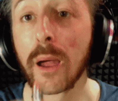 A Man With A Beard And Headphones Is Applying Lipstick To His Lips GIF