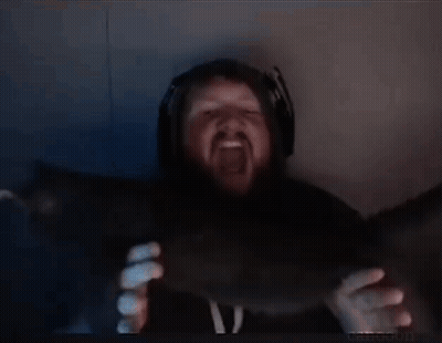 A Man With A Beard And Headphones Is Holding Something In His Hands In A Dark Room . GIF
