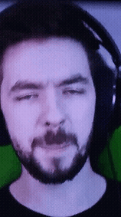 A Man With A Beard And Headphones Is Making A Funny Face . GIF